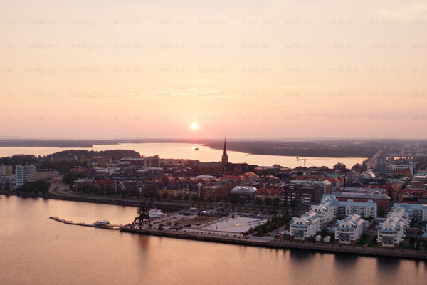 Sunset over Luleå city center by the riverfront with harbor cranes and modern housing