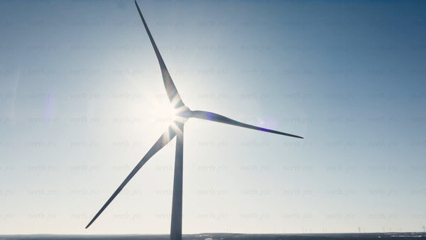 Rotating wind turbine against clear blue sky in winter