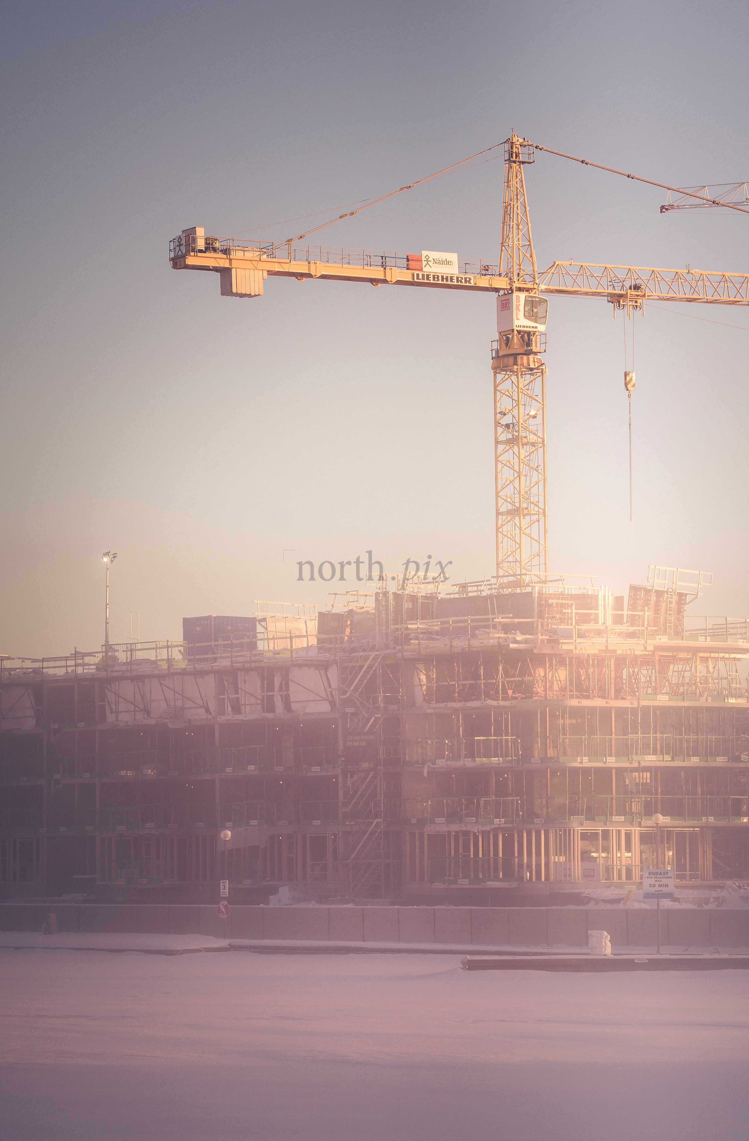 Tower crane over construction site at sunrise, winter