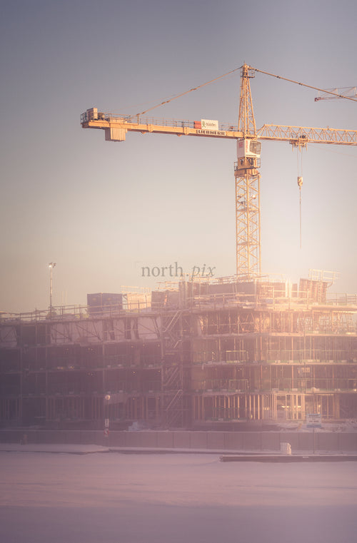 Tower crane over construction site at sunrise, winter