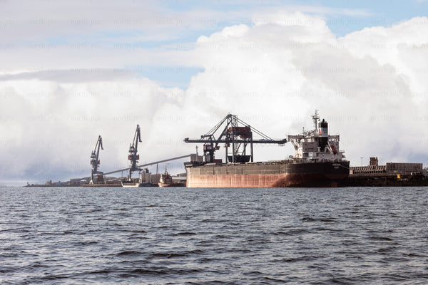 Cargo ship docked at industrial port with cranes