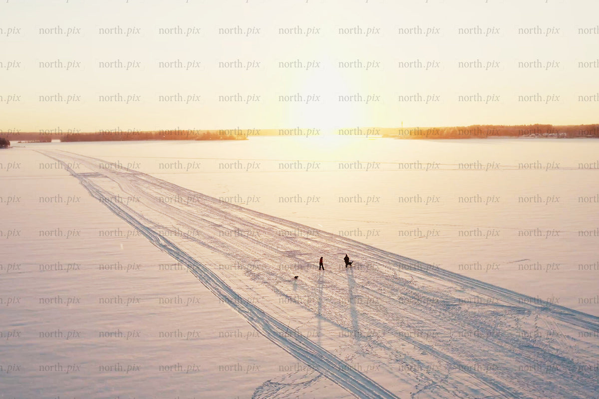 Sunset over snowy Luleå city center with tracks, people, and open winter horizon