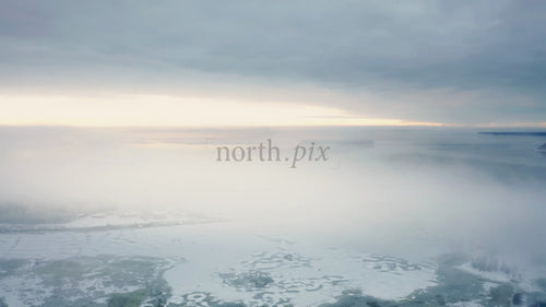 Flygfoto över Piteå Haraholmen på vintern: Snölandskap, iskallt hav och kustdimma