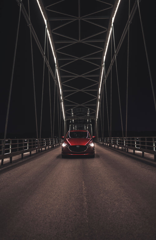 Red car on bridge at night