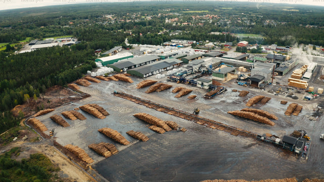 Aerial view of sawmill and lumber yard with stacks of logs in rural forest area