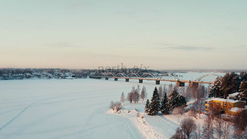 Vintersoluppgång över frusen flod och bro i Luleå, Sverige - Drönarvy från luften
